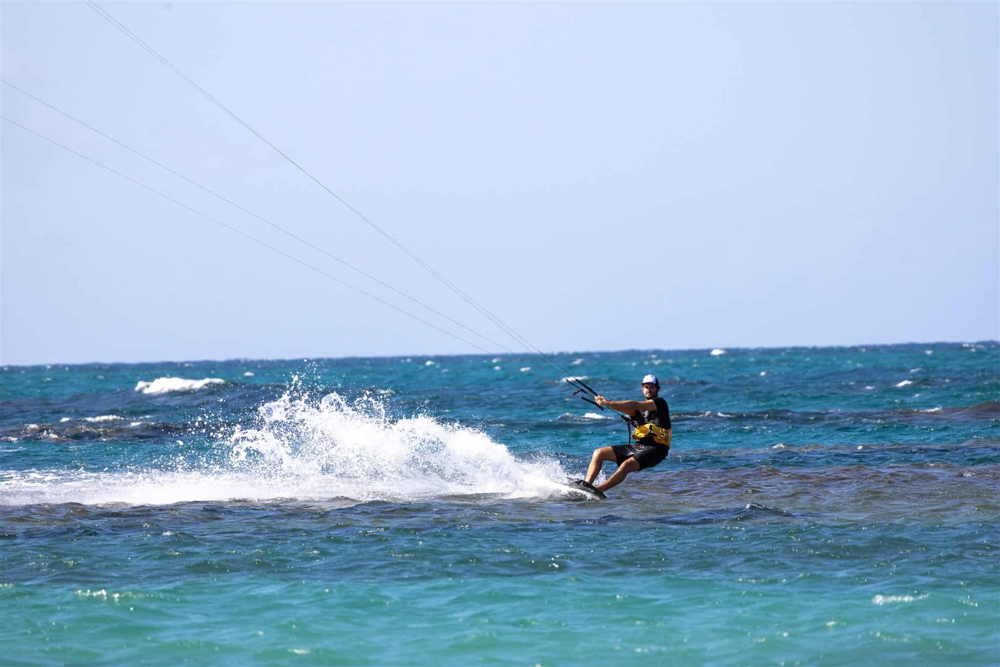 Fotógrafo capturando el movimiento de un kitesurfista en la playa.